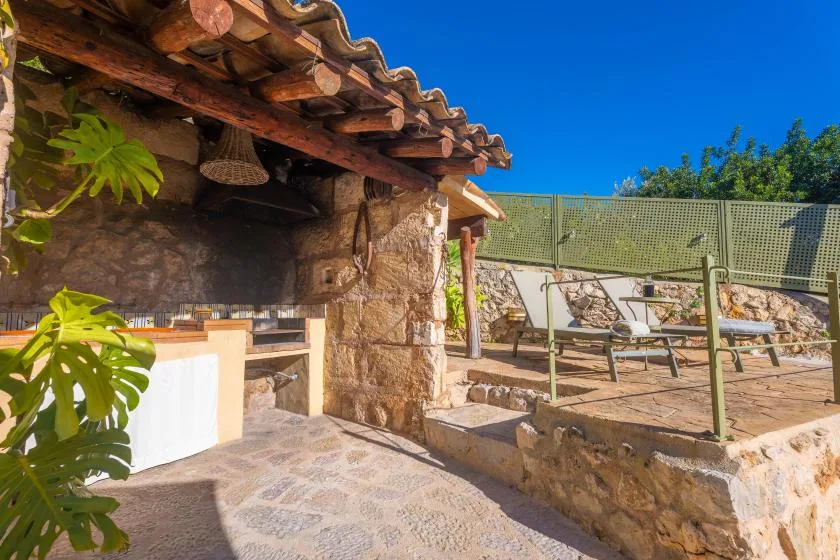 A stone patio with an outdoor seating area beneath a timber awning.