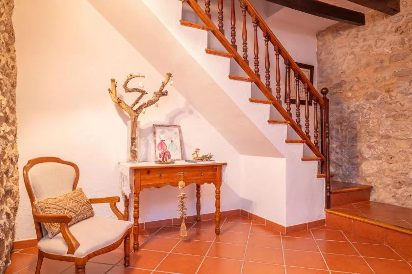 A tiled interior with a wooden staircase, a small table, and seating.