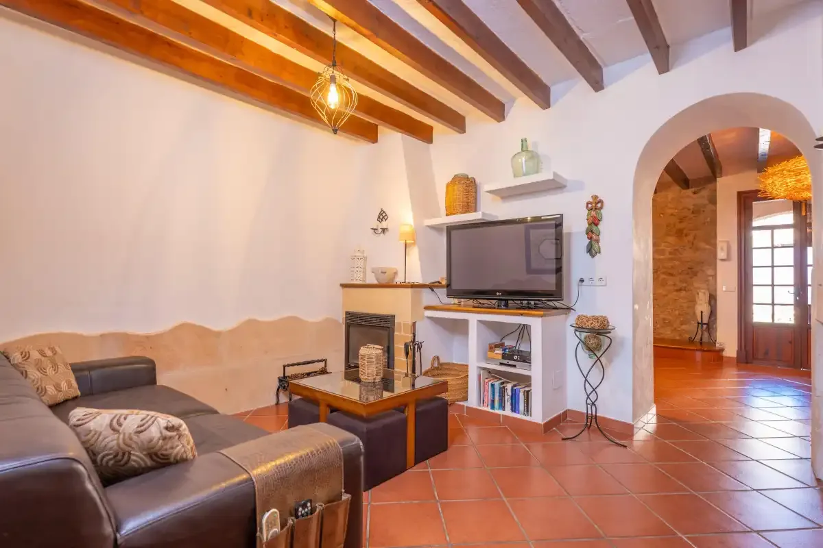 A living room with seating, a television, and exposed ceiling beams.