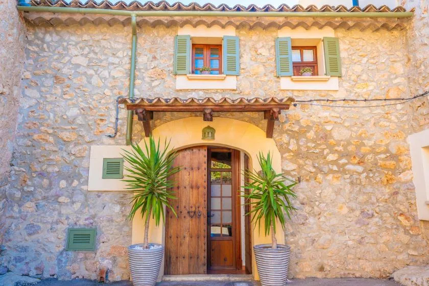 A stone building entrance with a wooden door and potted plants.