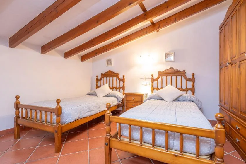 A bedroom with two wooden beds and exposed ceiling beams.