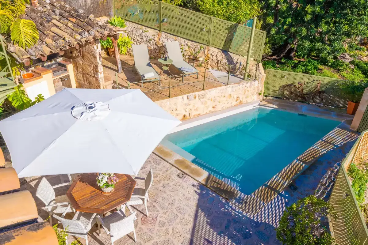 An outdoor pool beside a stone patio with seating and sun loungers.