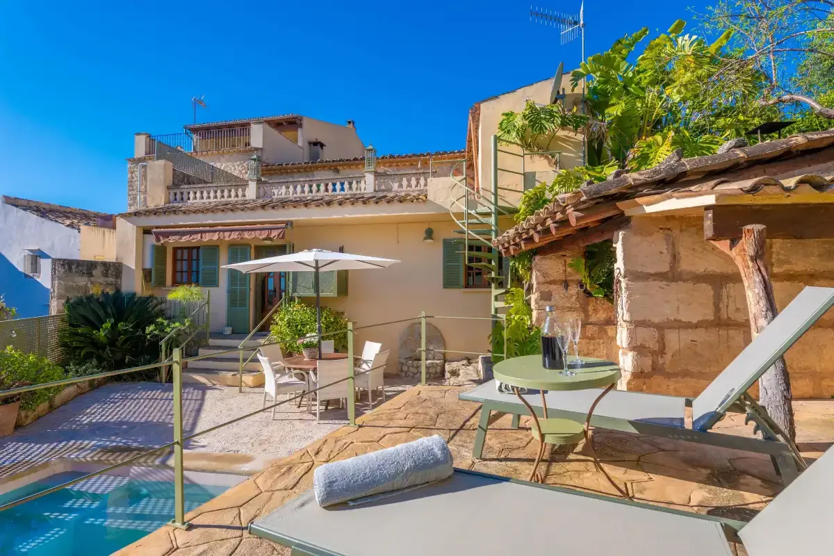 A sunny outdoor patio with seating, an umbrella, and a stone building.