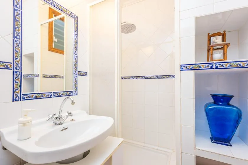 A tiled bathroom with a sink, mirror, and shower.