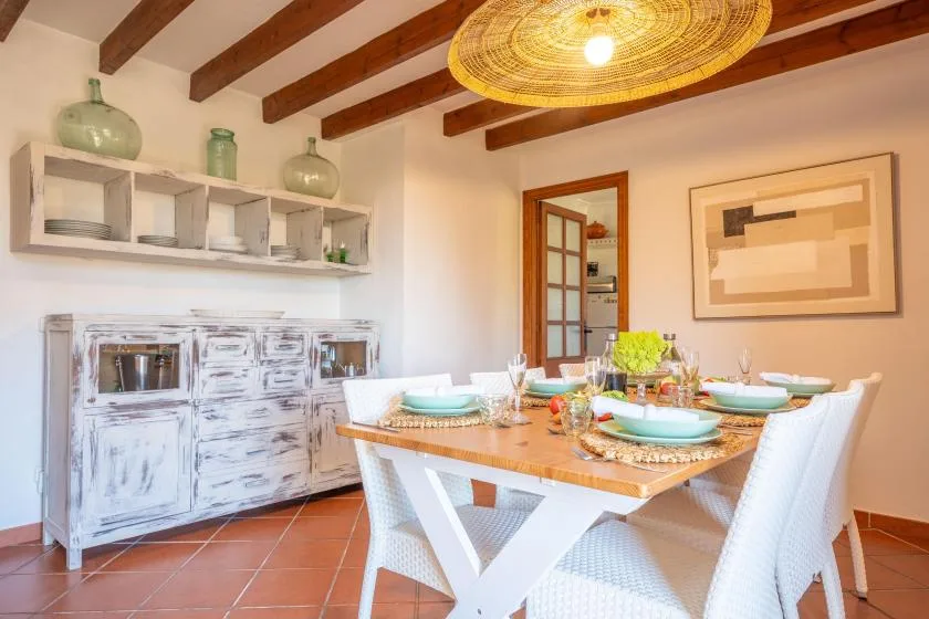 A dining room with a set table beneath exposed wooden ceiling beams.