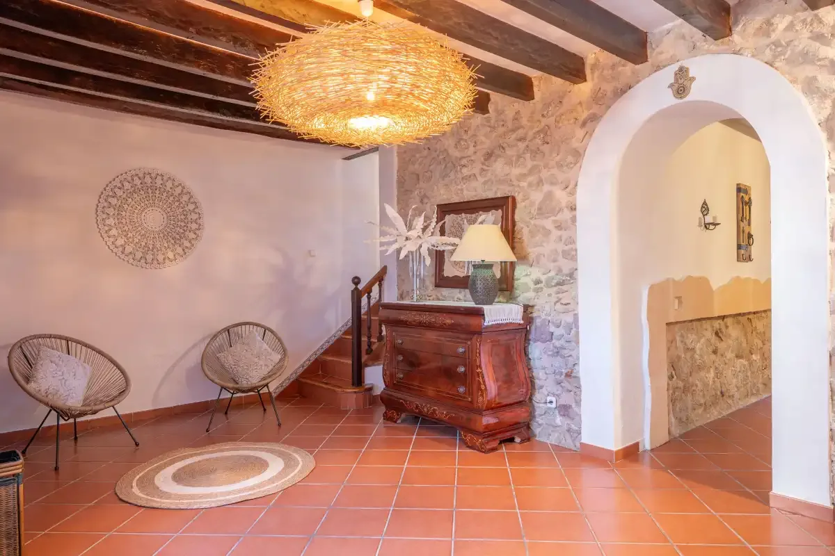 A rustic interior with tiled floors, woven seating, and a stone archway.