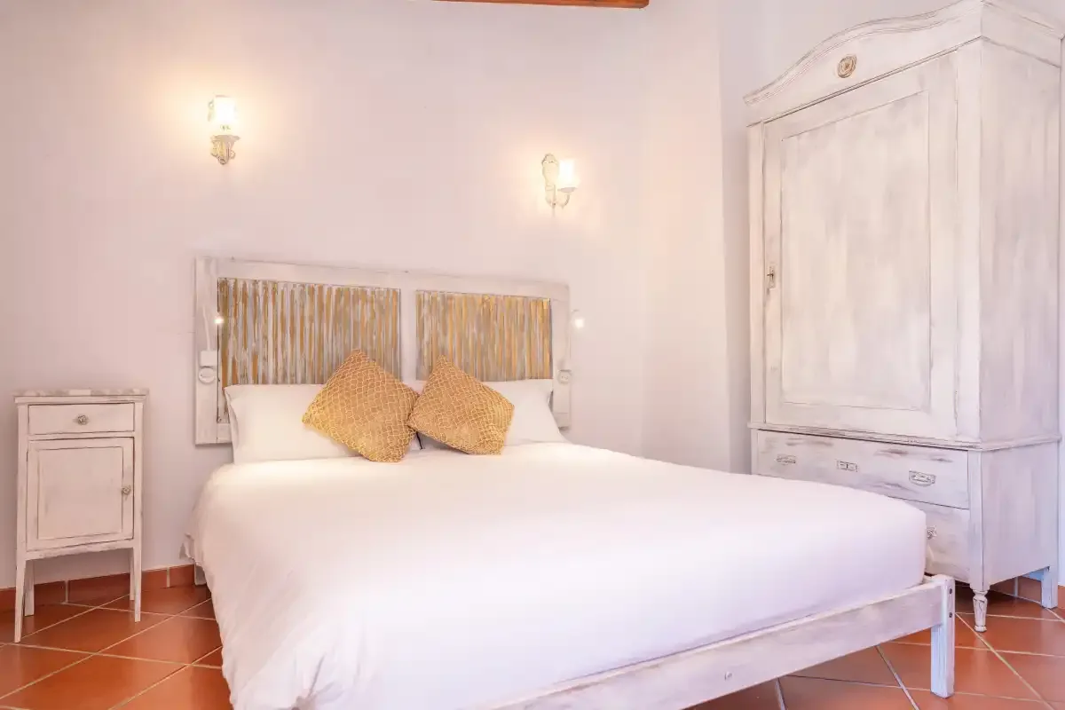 A bedroom with a white bed and matching painted wooden furnishings.