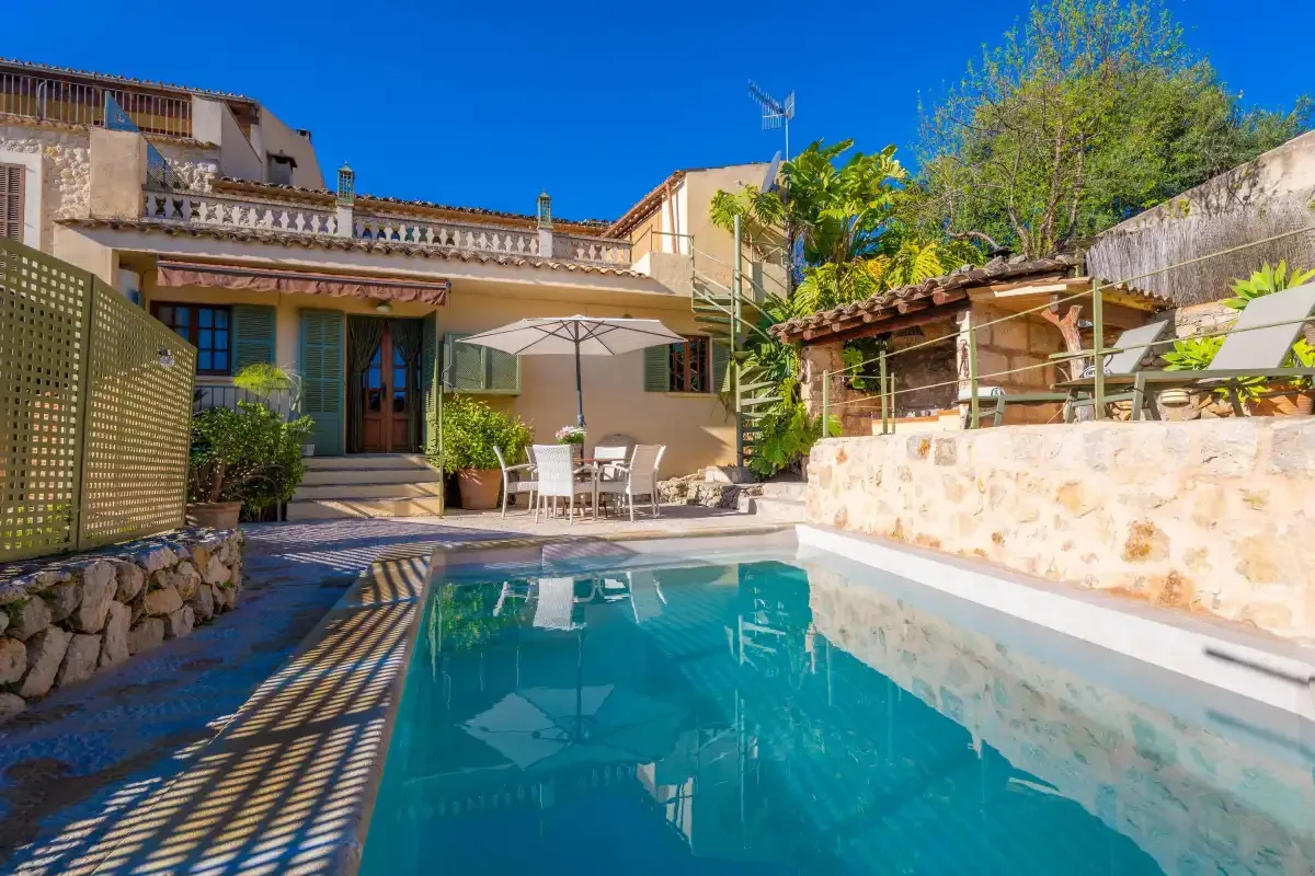 A swimming pool beside a patio with outdoor seating and a stone wall.