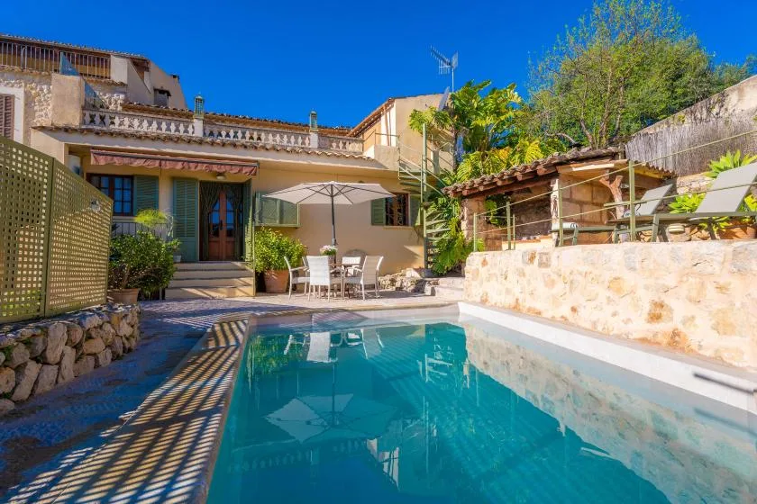 A swimming pool beside a house, with a patio seating area.