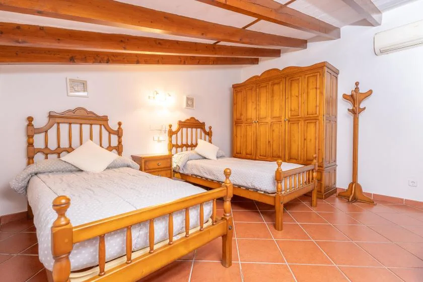 A bedroom with two wooden beds, a large wardrobe, and exposed ceiling beams.