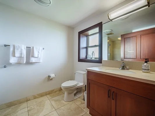 Un baño con inodoro, lavabo con mueble y espejo.