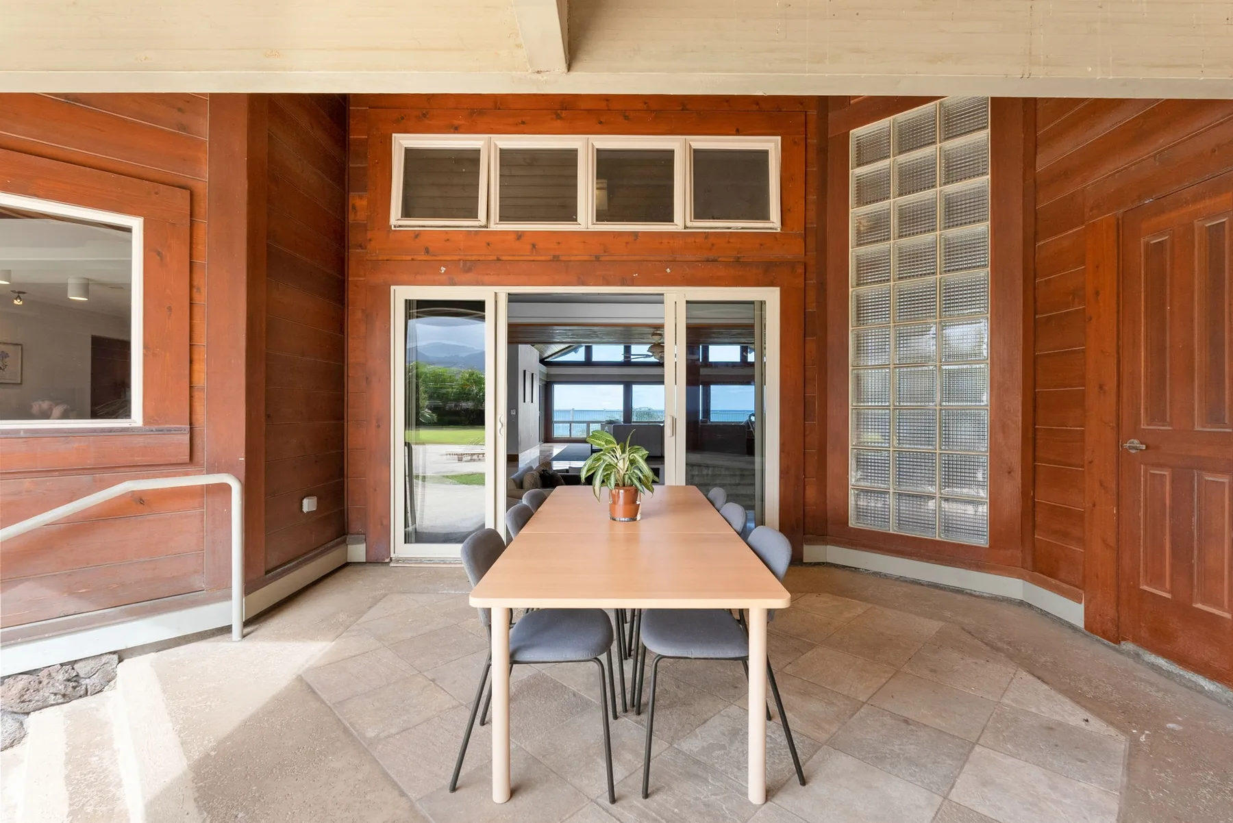 Un comedor revestido de madera con una mesa junto a grandes ventanas.