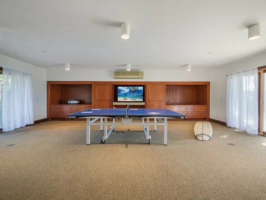 Una amplia sala de juegos cuenta con una mesa de ping-pong y armarios de madera.