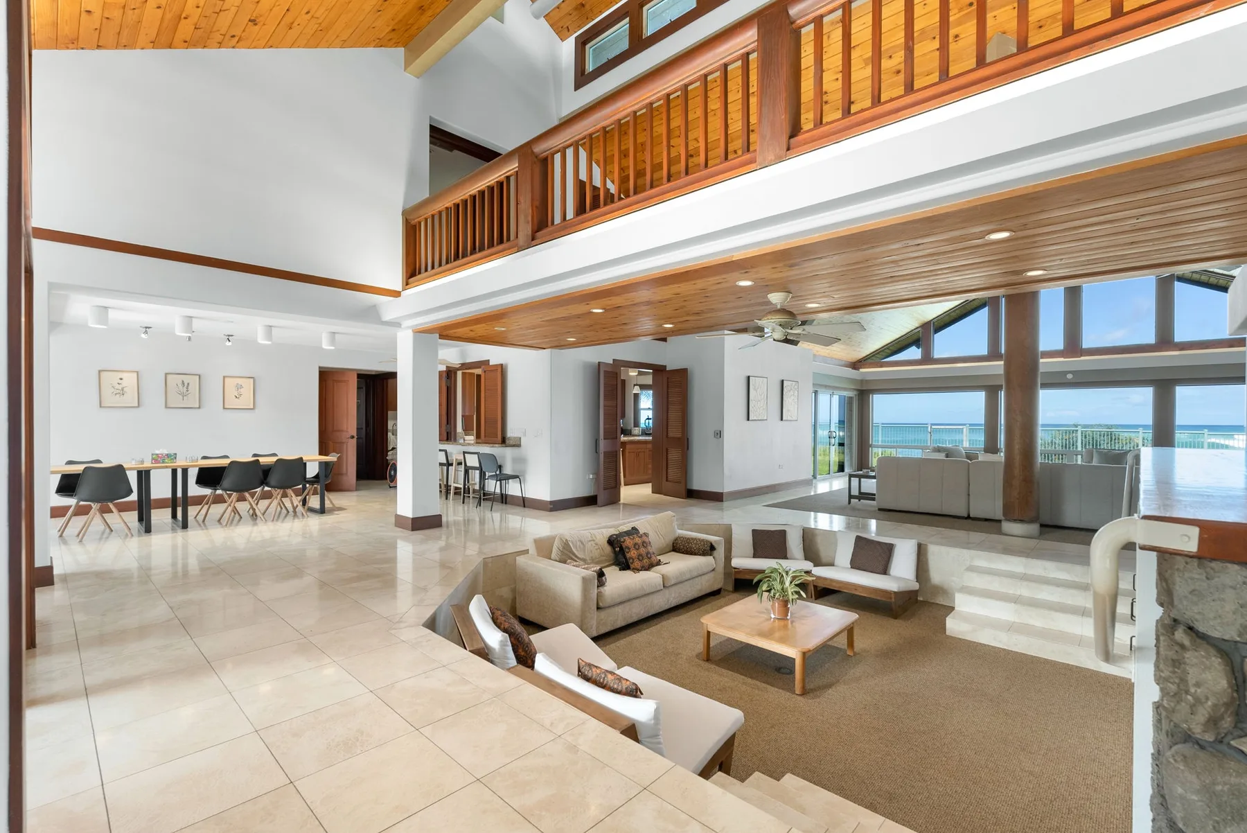 Una amplia sala de estar con asientos y grandes ventanas con vistas al agua.