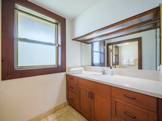 Un tocador de baño con un espejo amplio y una ventana.