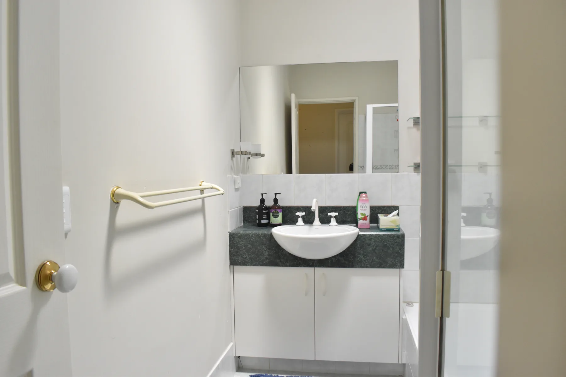 Un lavabo de baño con espejo y artículos de aseo sobre la encimera.