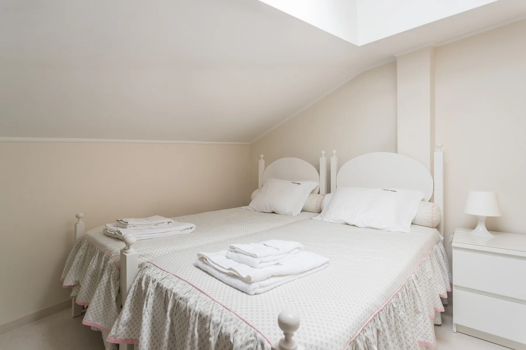 A bedroom with a neatly made bed and folded towels.