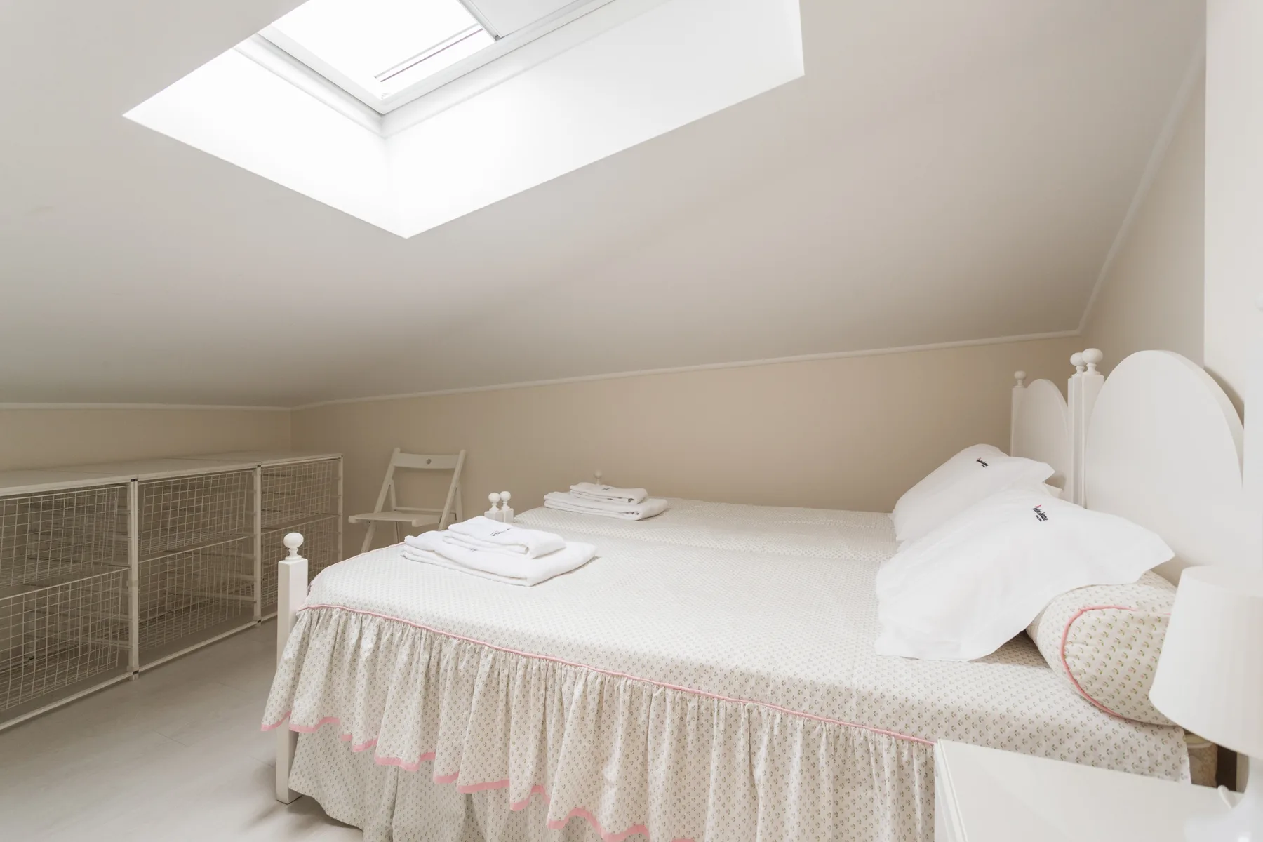 A bright bedroom with a bed beneath a skylight.