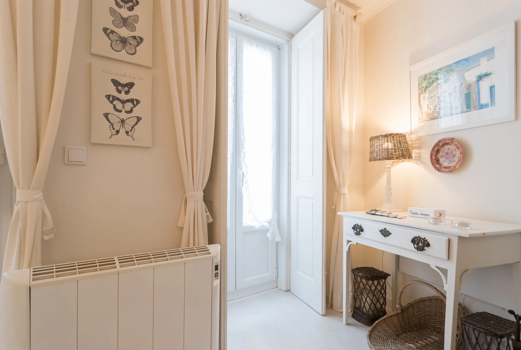 A bright room with a window, curtains, and a white console table.