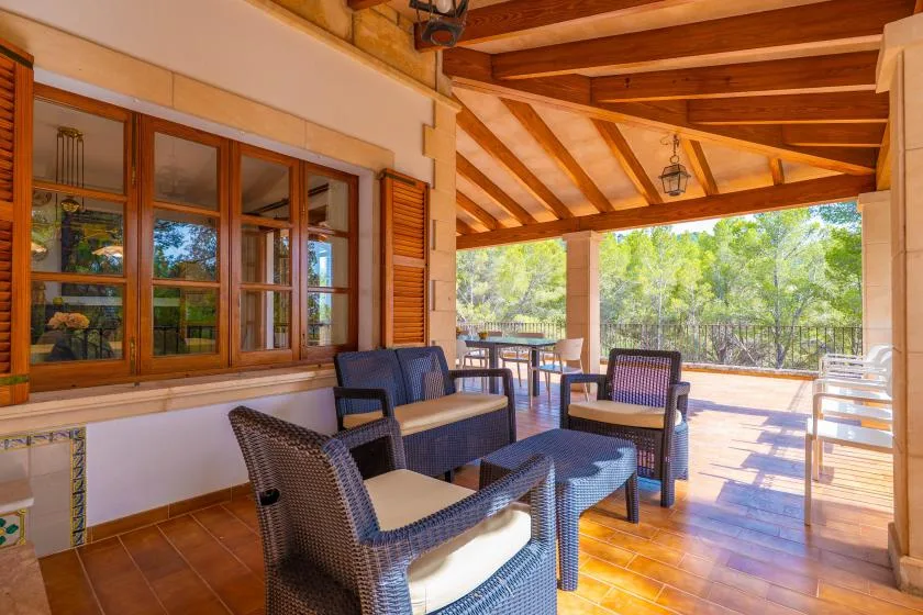 A covered outdoor seating area with wicker chairs and a table.