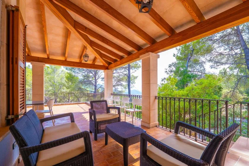 A covered outdoor seating area opens onto a tree-lined view.