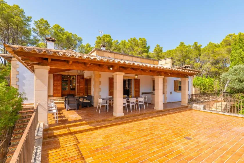A covered patio with outdoor seating opens onto a spacious tiled terrace.