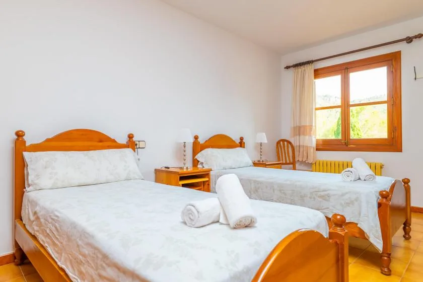 A bedroom with two beds, white linens, and a sunlit window.