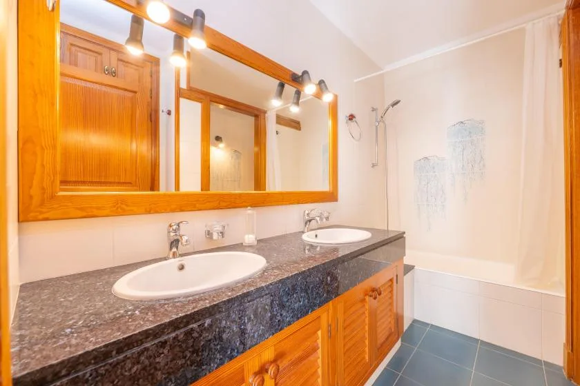 A bathroom with a double sink vanity and a shower.