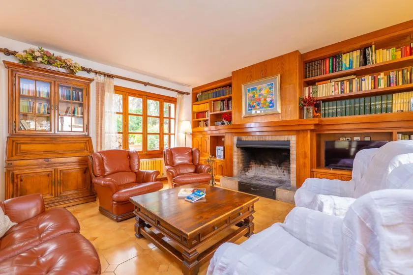 A living room with wooden bookshelves, a fireplace, and seating around a coffee table.