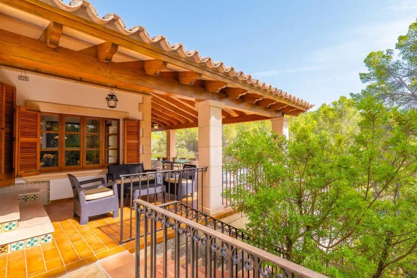 A covered outdoor terrace with seating overlooks leafy trees.