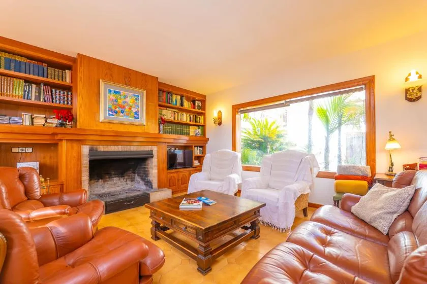 A living room with leather seating, a fireplace, and built-in bookshelves.