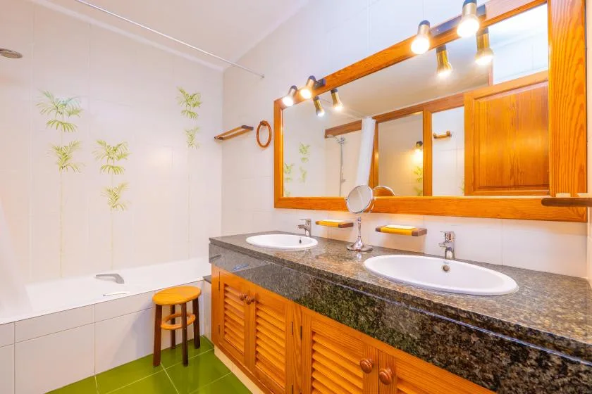A bathroom with a bathtub and a long vanity beneath a wide mirror.