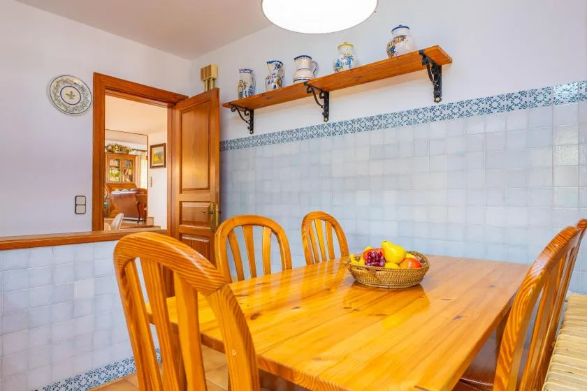 A dining area with a wooden table, chairs, and a fruit bowl.