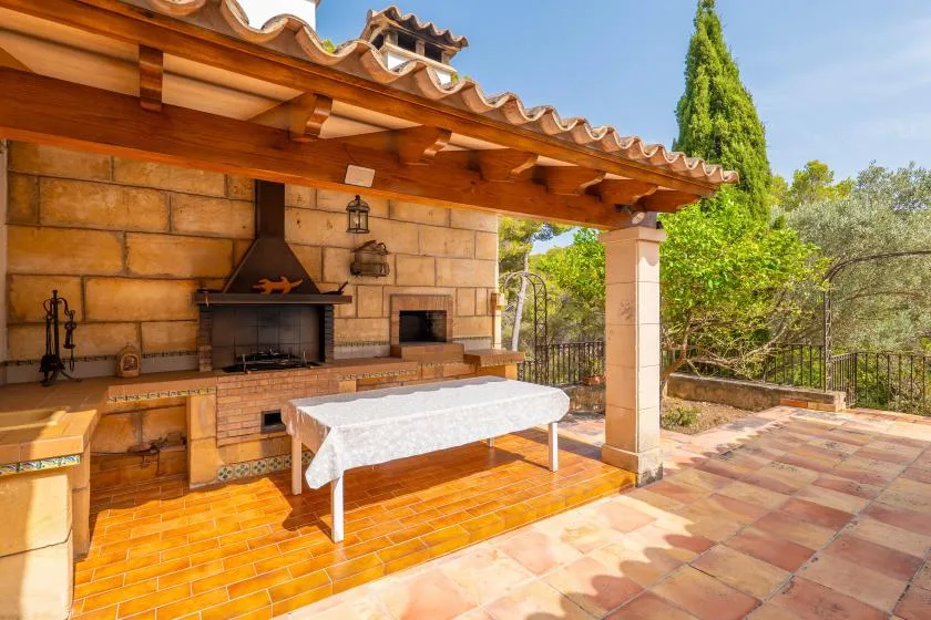A covered outdoor cooking area with a long counter and a table.