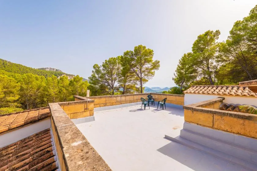 An open rooftop terrace with a few chairs and trees in the distance.