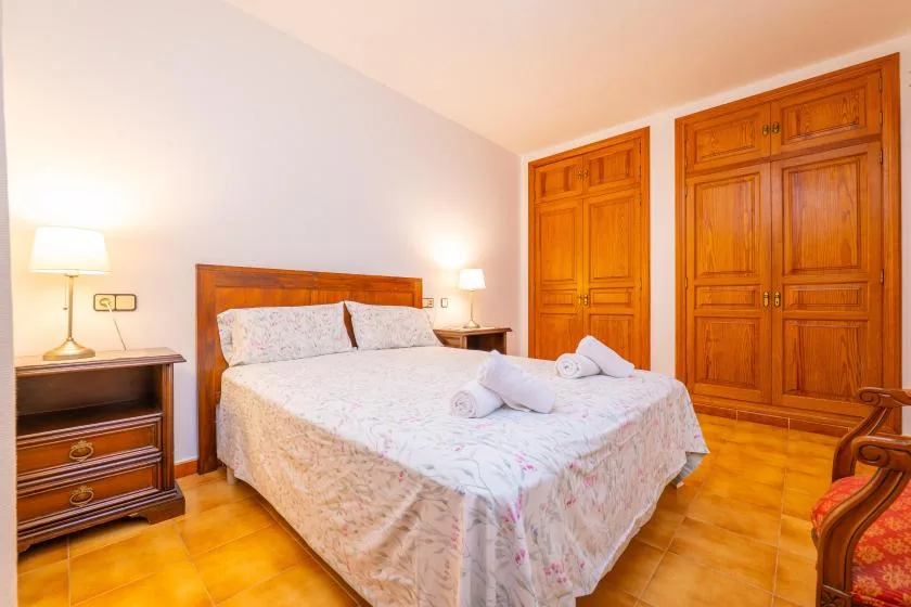 A bedroom with a double bed, bedside tables, and wooden wardrobes.