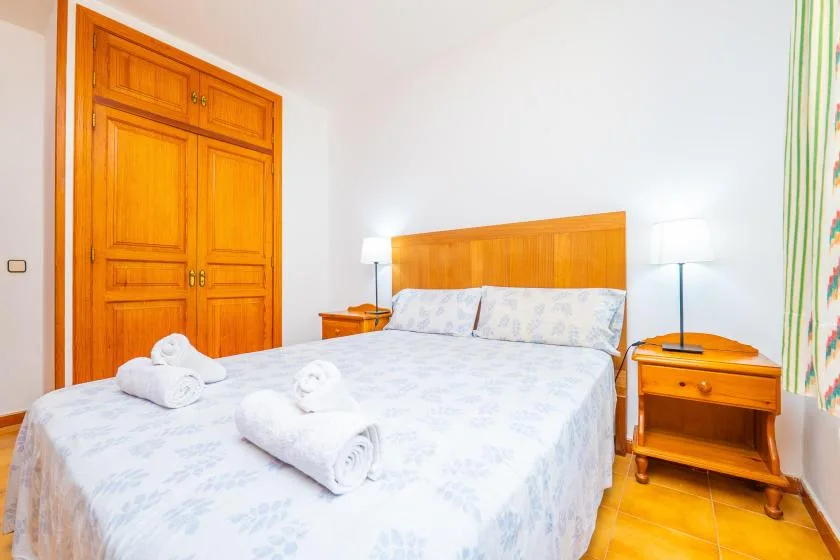 A bedroom with a double bed, wooden headboard, and matching bedside tables.