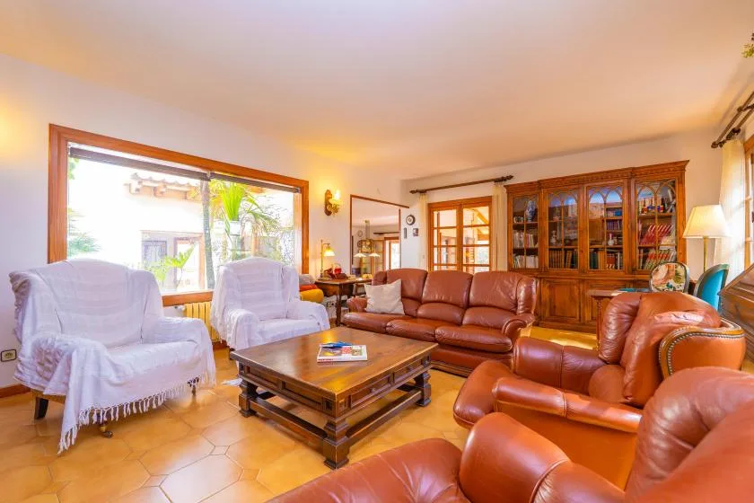 A living room with leather seating, a wooden coffee table, and a large window.
