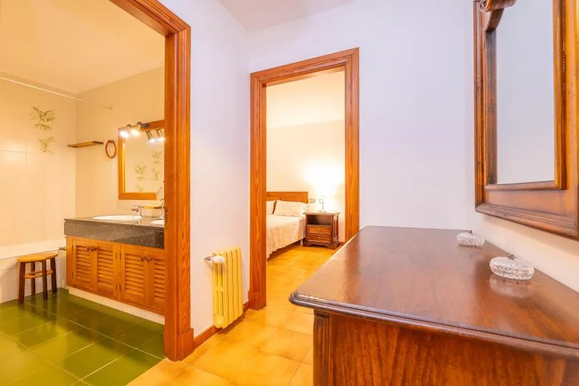 A bedroom and adjoining bathroom open onto a shared area with a wooden desk.