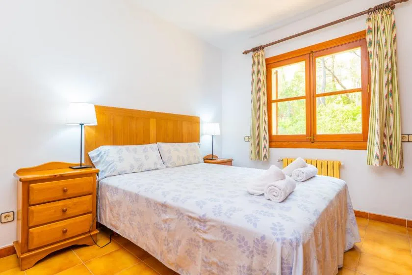 A bright bedroom with a double bed beneath a large window.