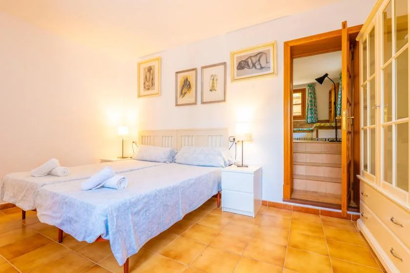 A bedroom with a bed, bedside tables, and an open doorway to a bathroom.