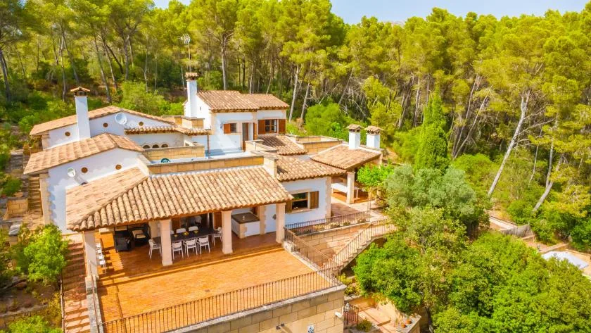 A large house with terracotta-colored roofs sits among trees.