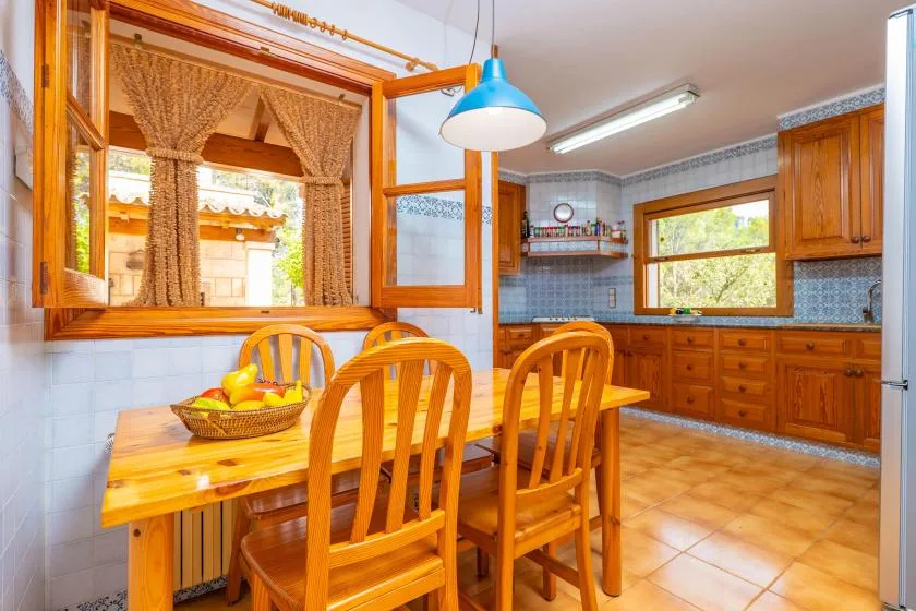 A kitchen dining area with a wooden table and chairs beneath a blue pendant light.