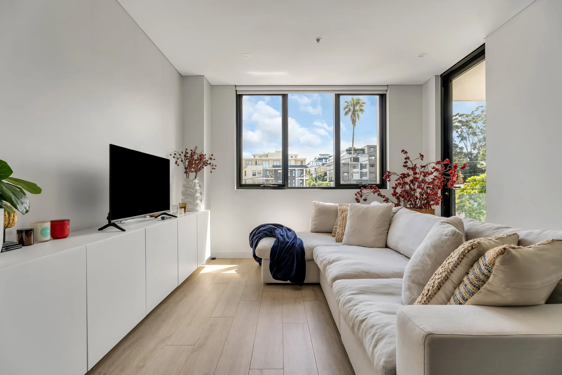 A bright living room with a white sectional sofa and television.