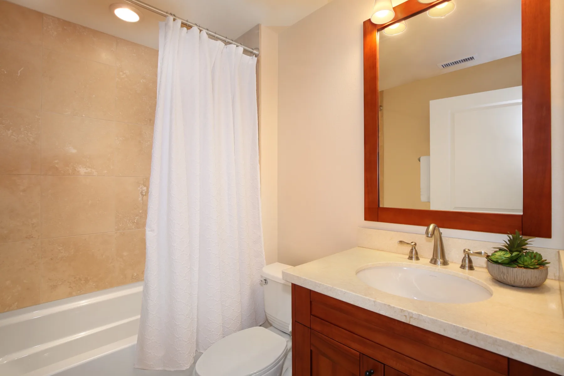Un baño con cortina de ducha y un lavabo bajo un espejo grande.