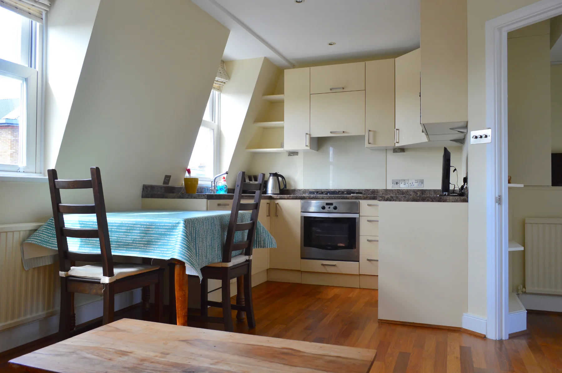 A bright kitchen and dining area with a table beside the windows.