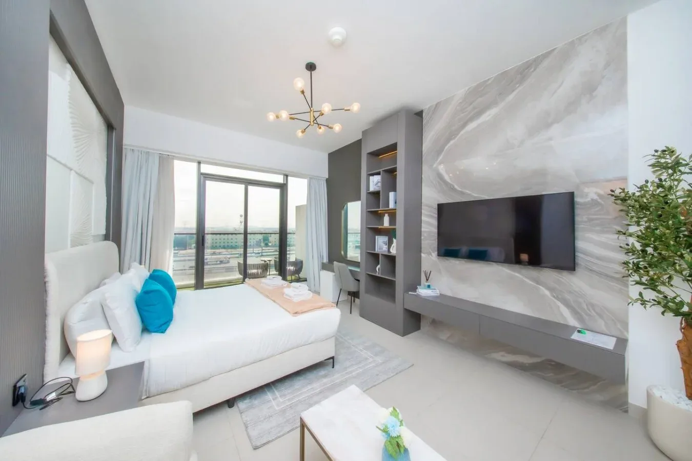 Sala de estar moderna con asientos, un televisor en la pared y puertas al balcón.