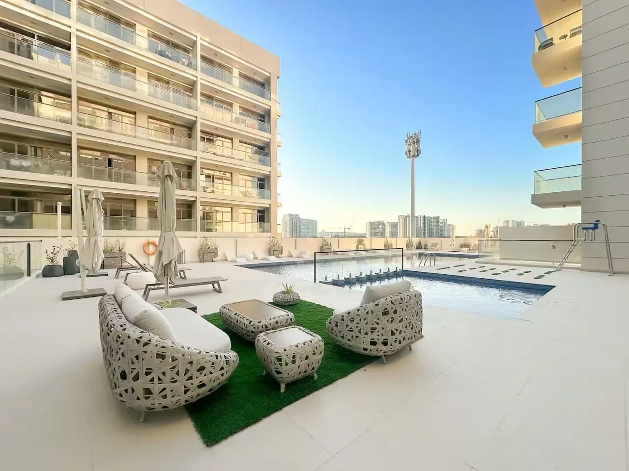 Una terraza con piscina al aire libre, asientos y edificios de apartamentos al fondo.