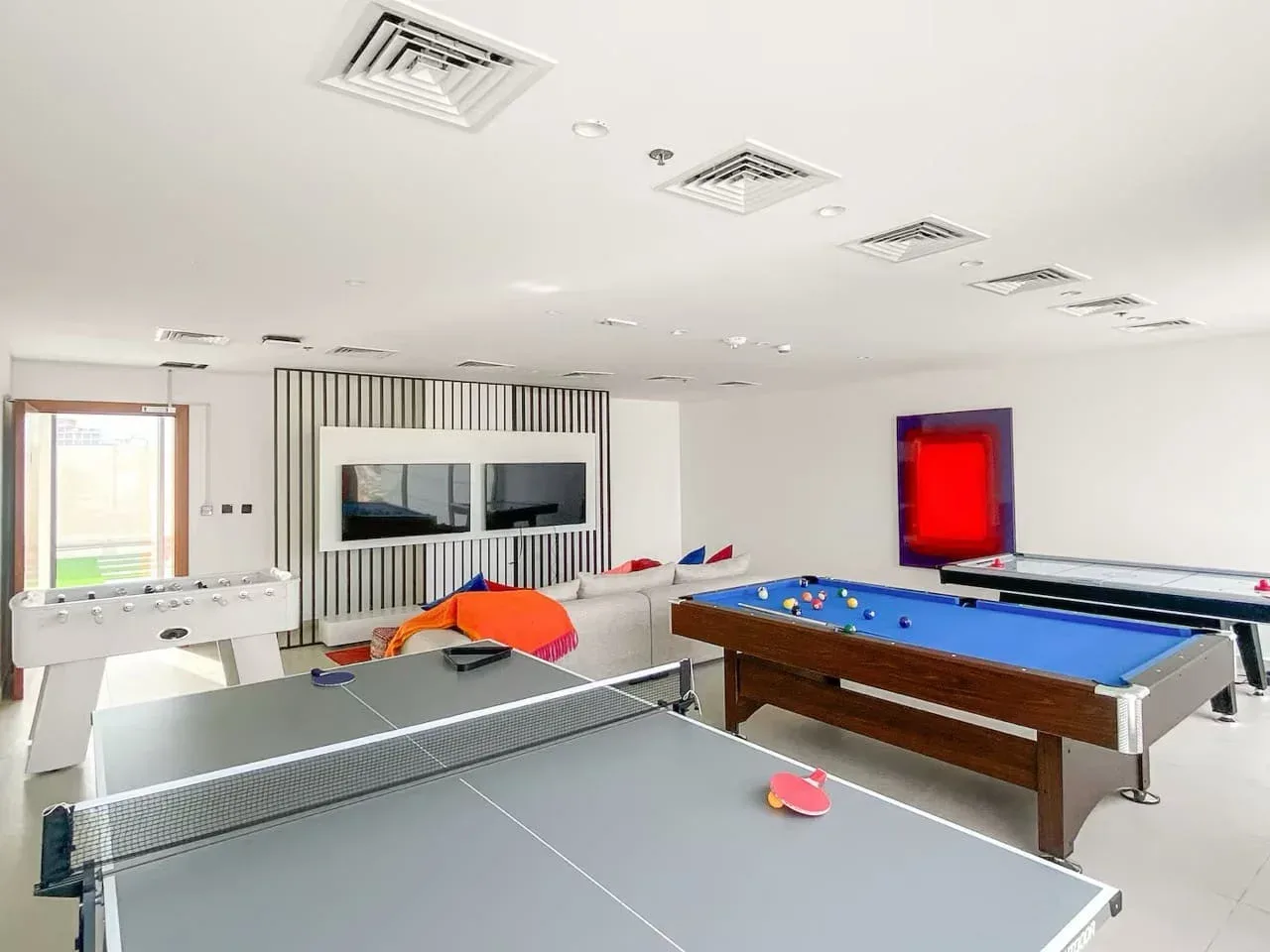 Una sala de juegos con una mesa de billar y una mesa de ping-pong.
