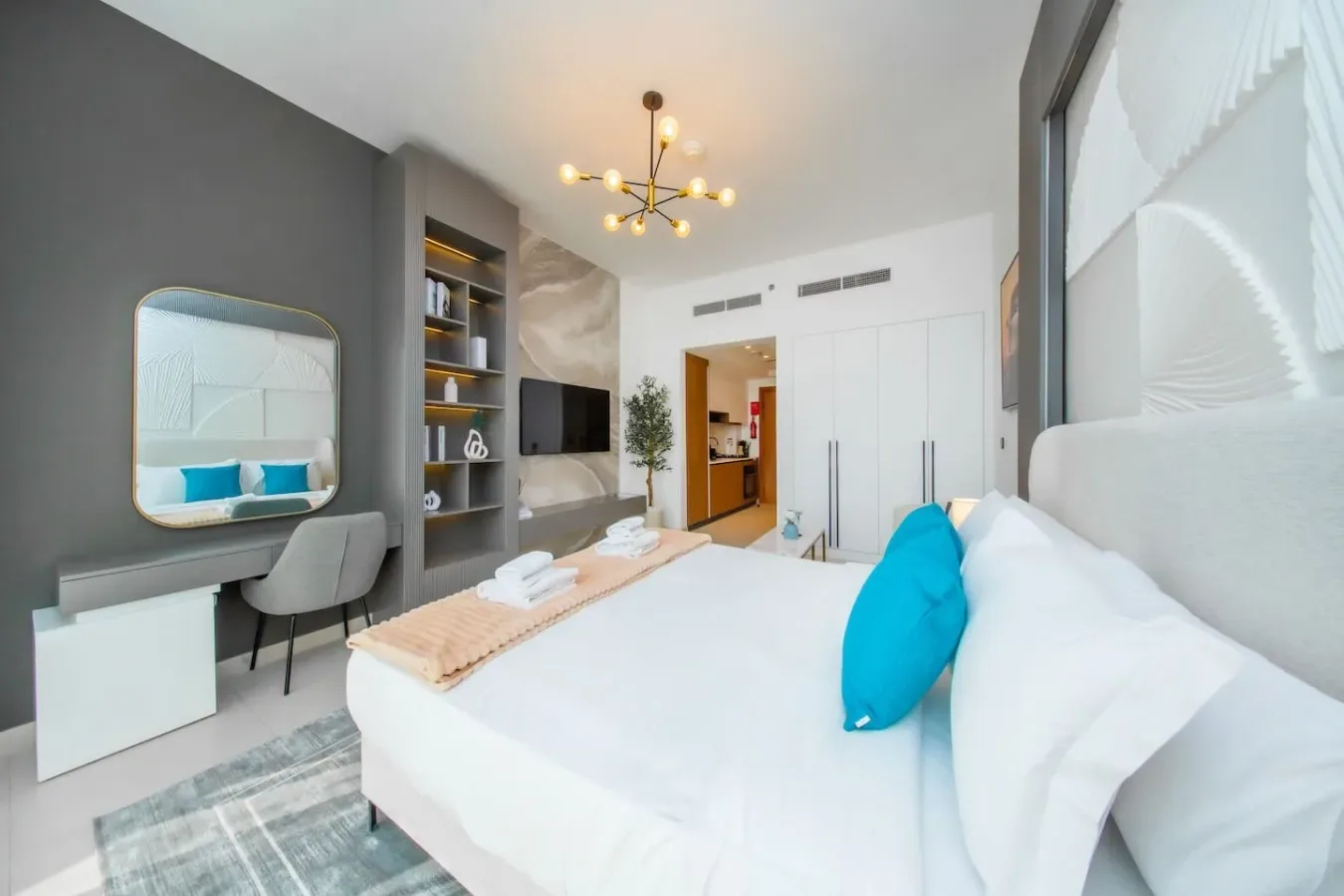 Un dormitorio luminoso con una cama grande, estanterías empotradas y un escritorio.